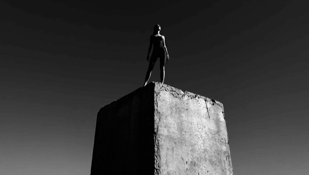 Gen4 A wide-angle shot of a woman standing on a concrete block, looking up from below 318575680
